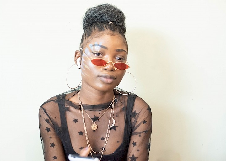 Young woman wearing red sunglasses.